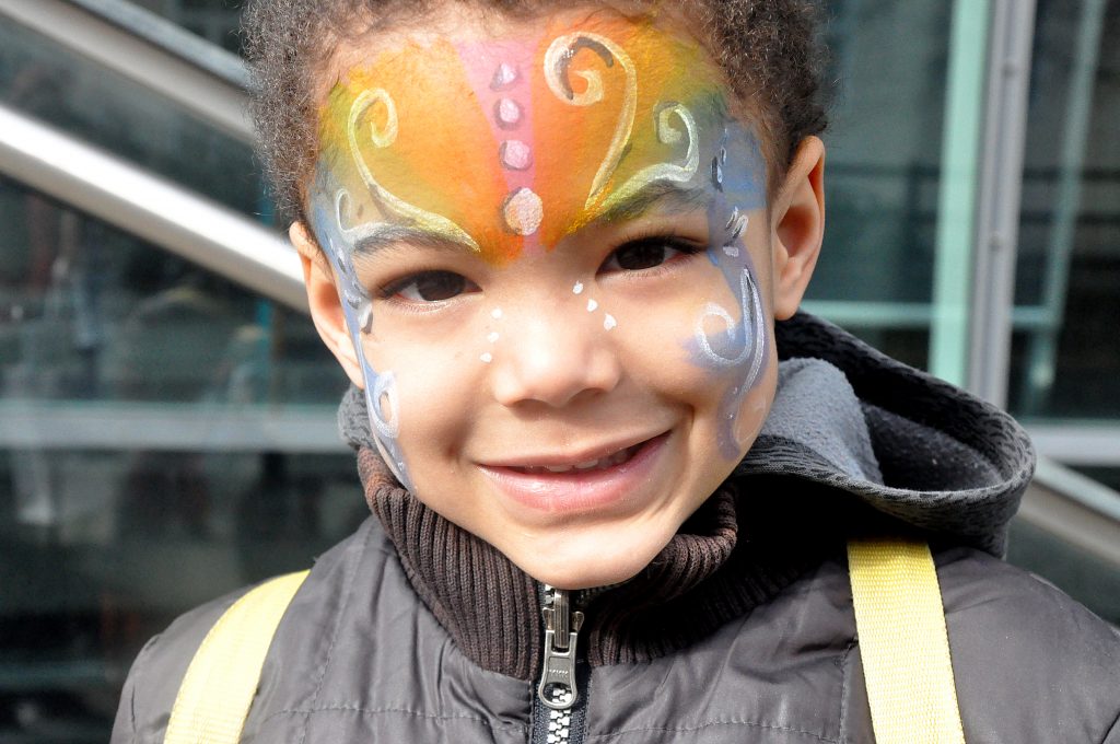 a small boy with colorfully painted face